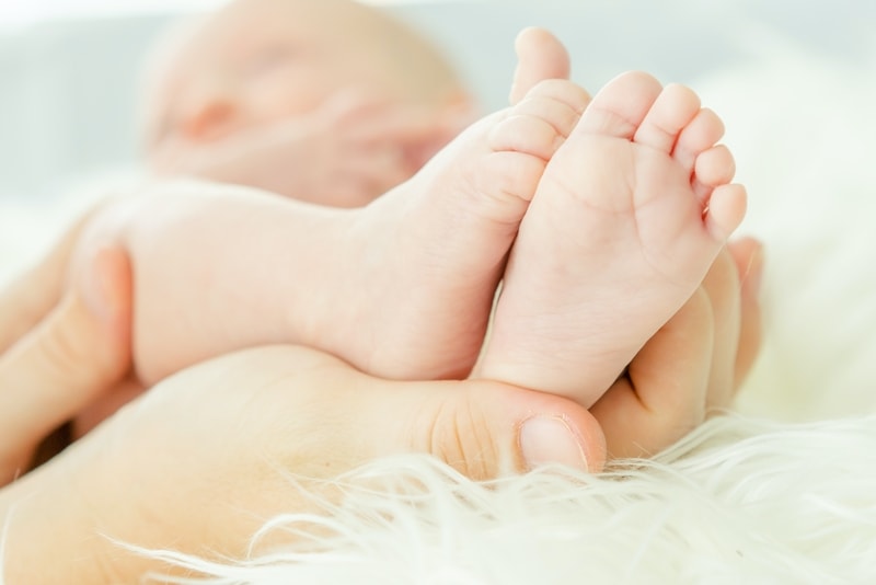 Mama voelt aan baby’s voetjes om te achterhalen of de temperatuur in de babykamer goed is – Renson.
